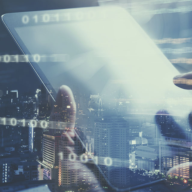 Ręka trzymająca tablet z interfejsem cyfrowym i nałożonymi danymi binarnymi na tle panoramy miasta